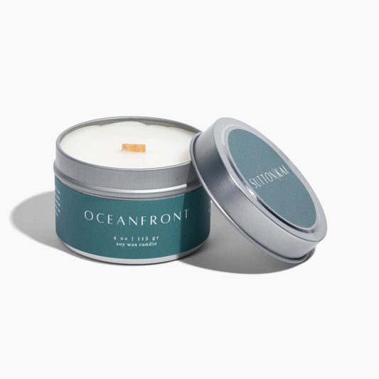 Candle in a tin with 'Oceania' branding on a white background