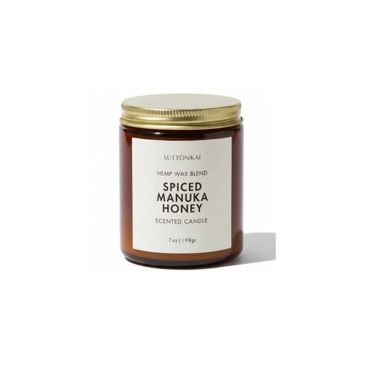Scented candle labeled 'Spiced Manuka Honey' with a gold lid on a white background