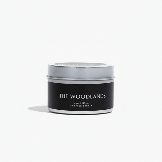 Candle jar with 'The Woodlands' branding on a white background